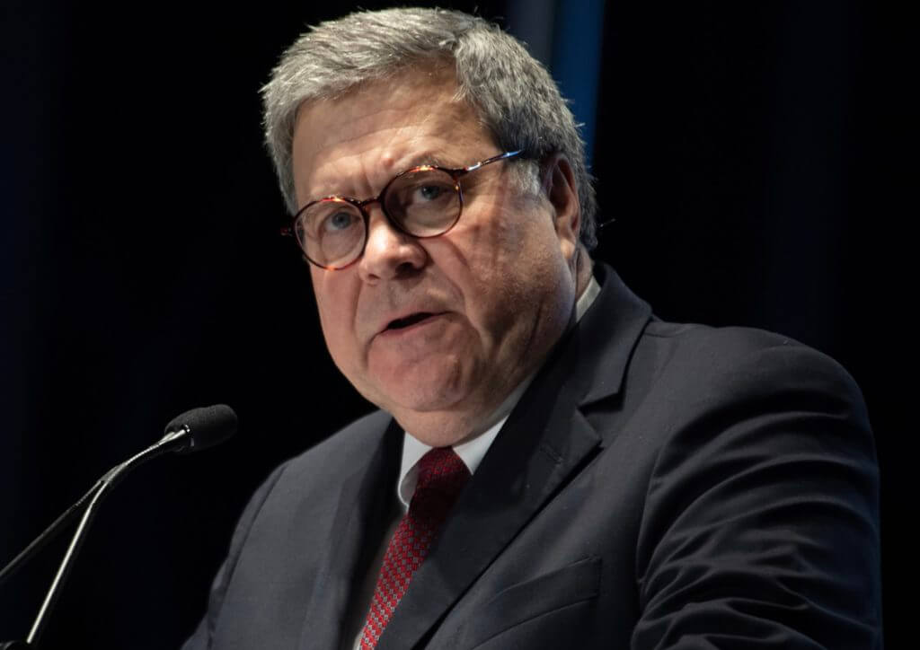 A man in suit and tie sitting at a podium.