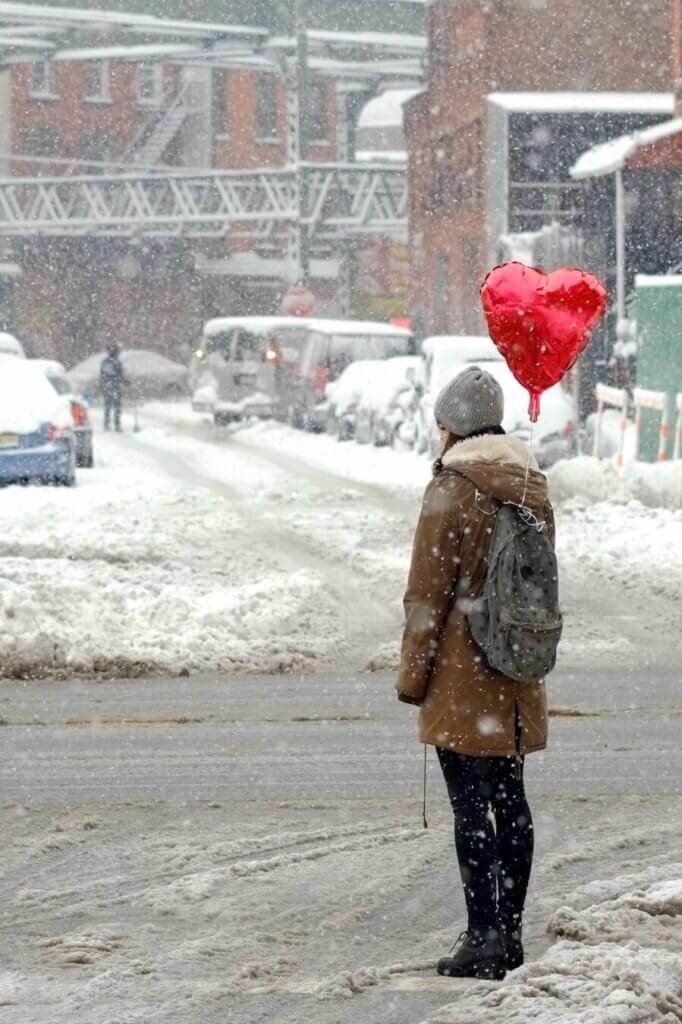 A person with a heart shaped balloon in the snow.